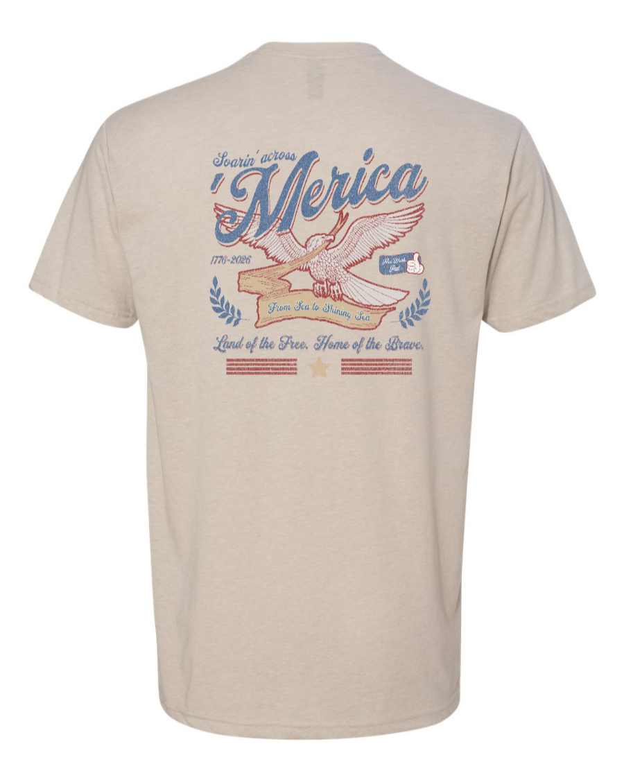 Next Level T-shirt featuring a patriotic design from Corner of Main, with a sand-colored background and "Soarin' Across 'Merica" print.
