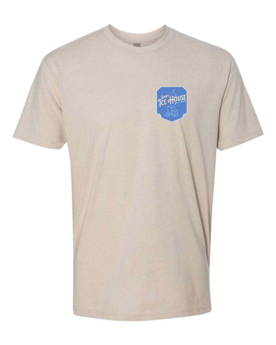 Corner of Main Sven's Ice House Next Level T-Shirt in sand color, featuring a left chest graphic design.