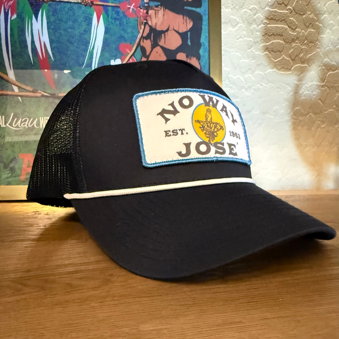 Black cap with a patch reading 'No Way Jose' on a wooden surface.