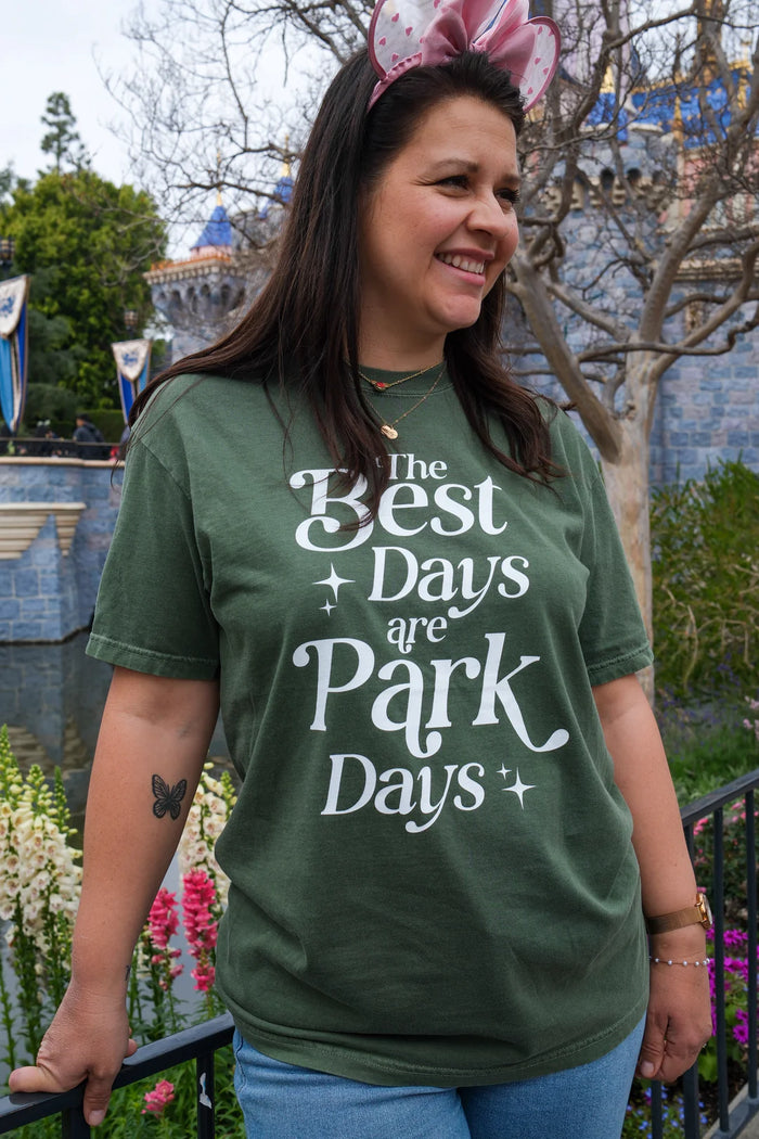 Woman in a green Best Days Are Park Days tee near Sleeping Beauty Castle
